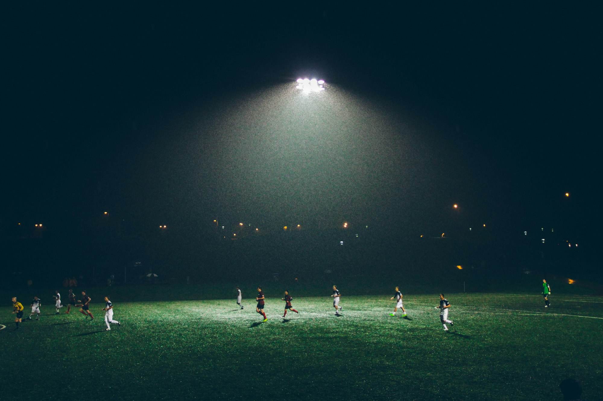 Fußballspiel auf einem großen Platz bei Nacht unter Flutlicht